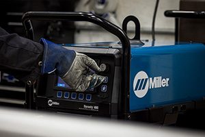 gloved hand pressing a button on a welding machine