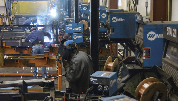 Welding operators in shop with wire feeders mounted at each welding station