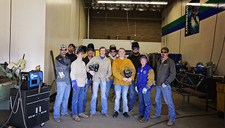 Group of welding students standing in welding lab with equipment