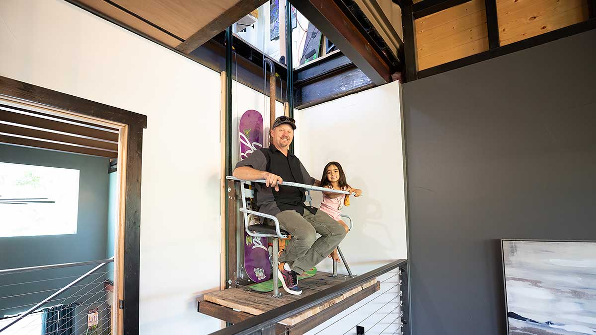 Shane Barber and his granddaughter inside of home made by welding shipping containers together
