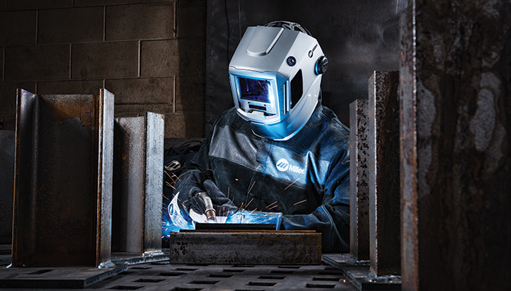 Welding MIG welding a piece of metal wearing welding safety gear