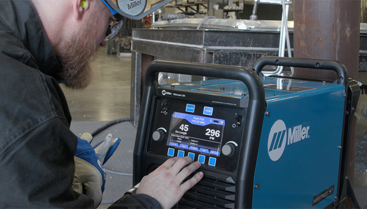 Operator uses the interface screen to set up Millermatic® 355 MIG welder