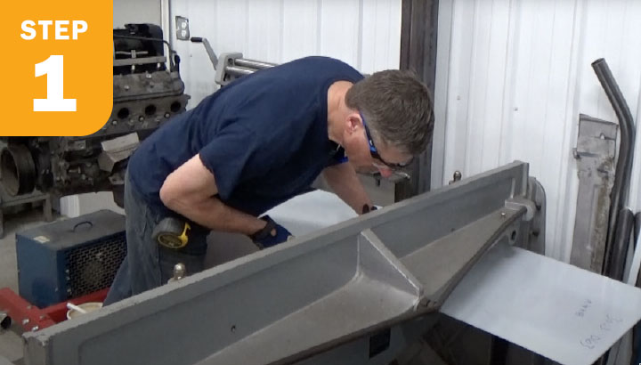 Operator cutting sheet metal with a stomp shear in a shop