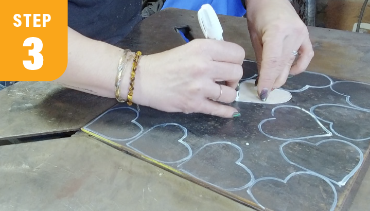 Metalworker crafting heart shapes from sheet metal